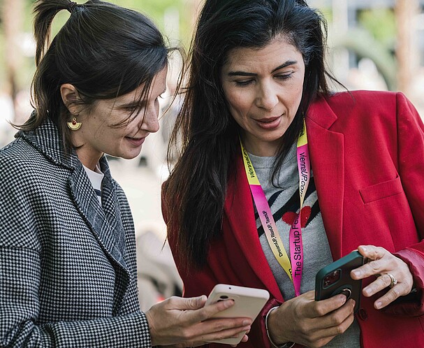 Two women talking to each and looking at a phone