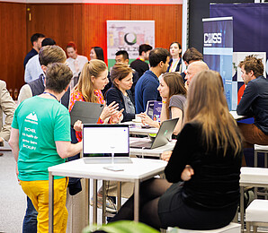 Several people are standing or sitting opposite one another and having brief conversations as part o