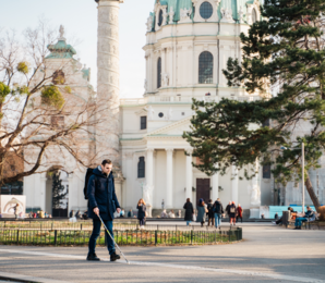 A person with a white cane is using a tactile guidance system in front of Charles’s Church
