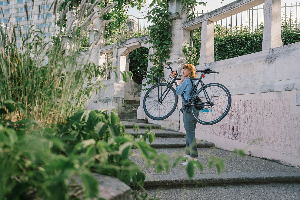 Woman carrying a bike in a park