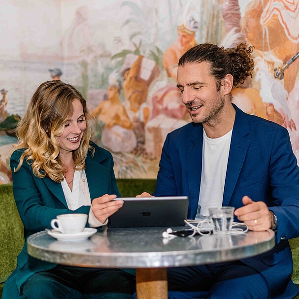 Eine Frau und ein Mann sitzen gemeinsam an einem Tisch und arbeiten an einem Computer