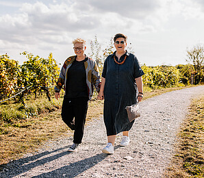 Two smiling women walking in a vineyard in the sun