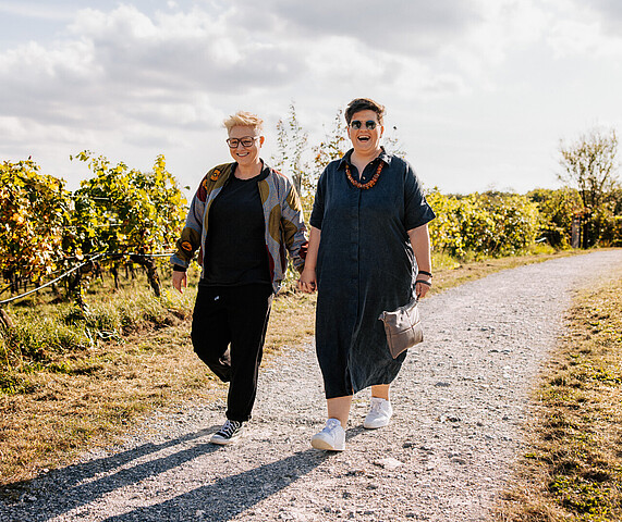 Two smiling women walking in a vineyard in the sun