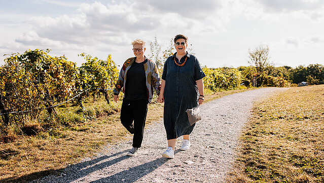 Two smiling women walking in a vineyard in the sun