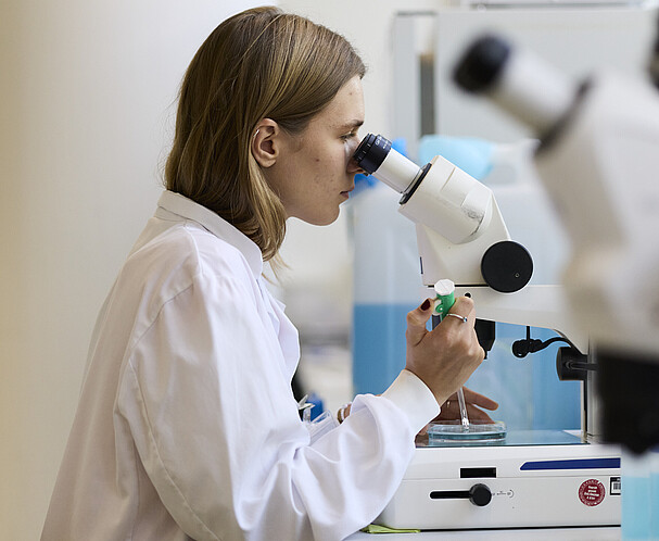 Microscope A woman in a lab coat looking into a microscope