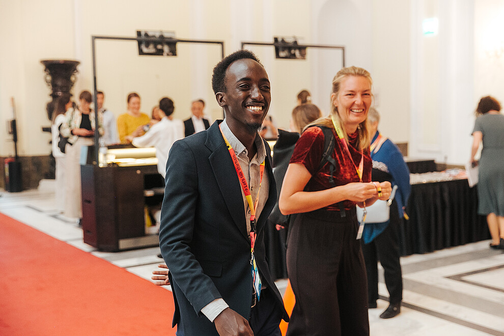 A man and a woman laugh as they walk through the lobby of the Impact Days, an event that is part of startup festival ViennaUP.