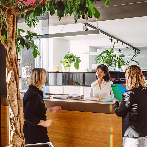 A receptionist talking to two women at a desk 