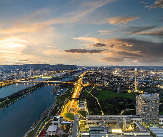 A view of the city of Vienna at sunset, with the lights of buildings and cars lighting the sky. 