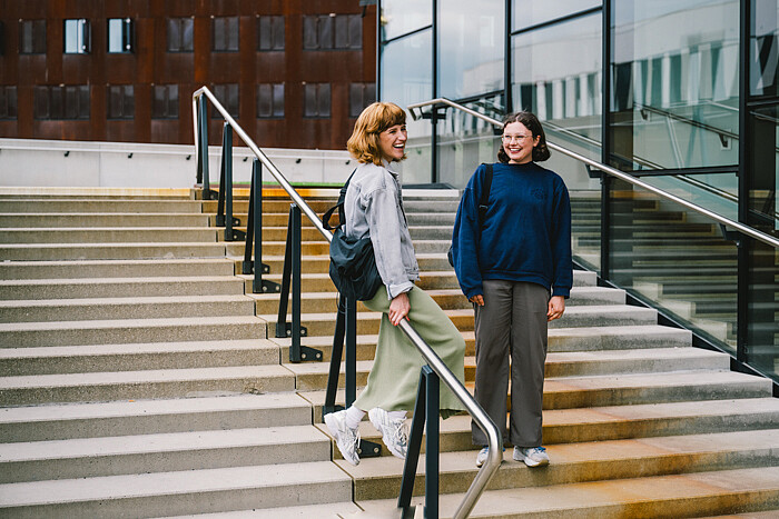 Two women talking and smiling on some steps