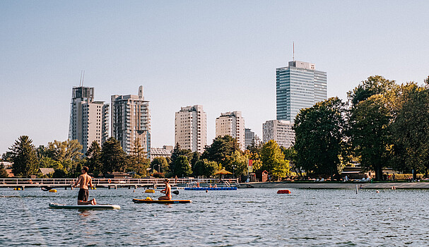 2 standup paddlers on the Danube in front of the skyline