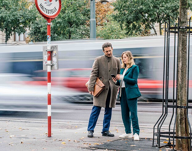 Man and woman standing at the street while tram is passing by 
