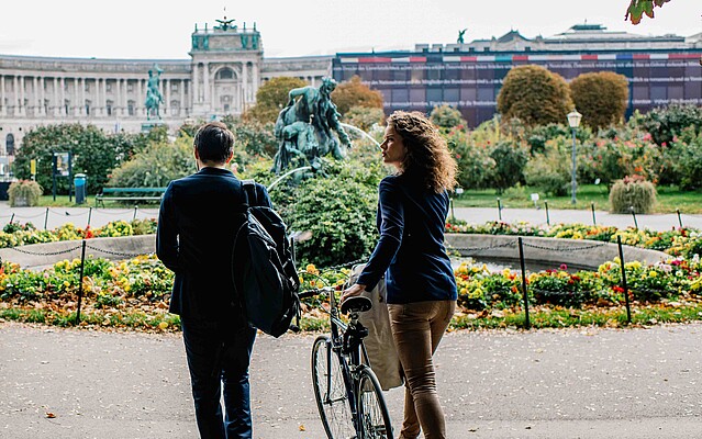 Man and woman walking with a bike in Vienna's Burggarten