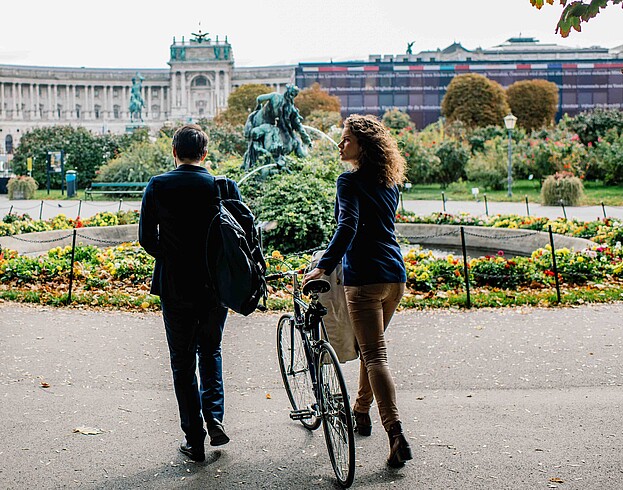 Man and woman walking with a bike in Vienna's Burggarten