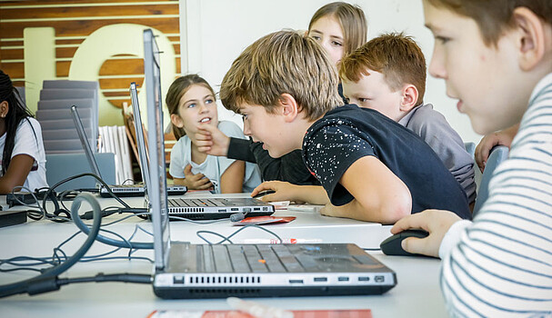 Workshop für Schulklassen und Familien. Eine Gruppe Kinder arbeitet an Laptops