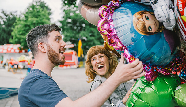 Man and woman with balloons smiling 