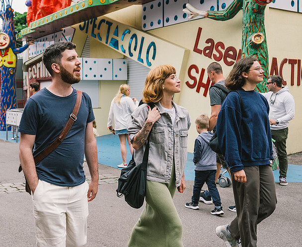 Three young people a man and two women walking into the amusement park Wiener Prater