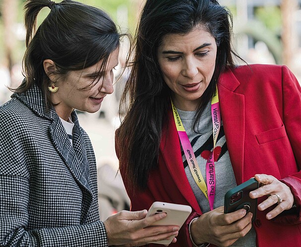 Two women talking to each and looking at a phone