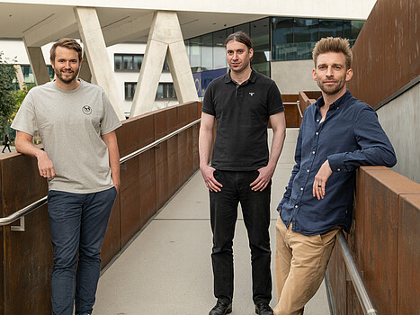 Three men posing inside a building.