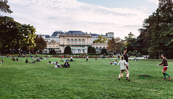 Green field in Stadtpark with kids and people playing