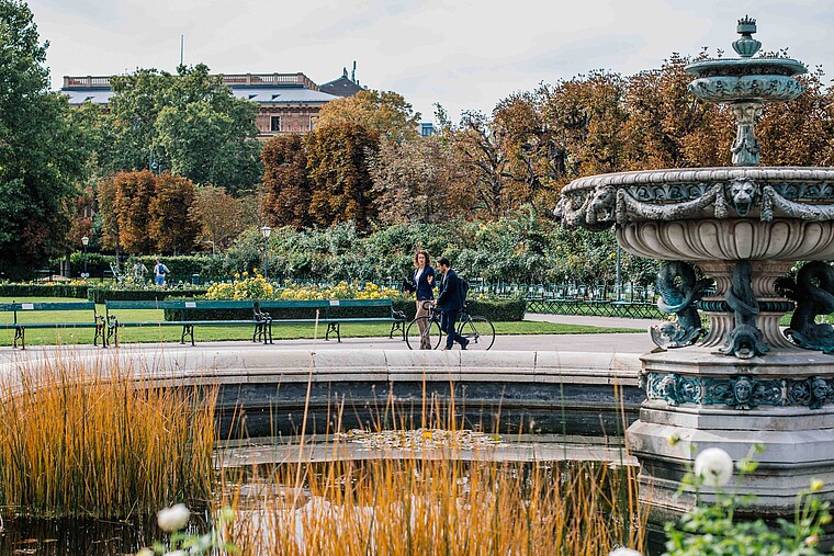 Man and woman walking by a fountain in park