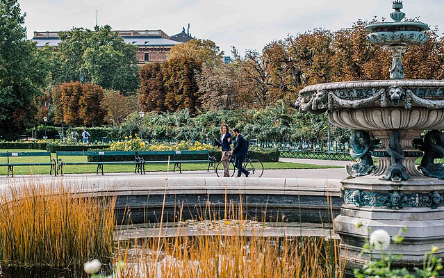 Man and woman walking by a fountain in park