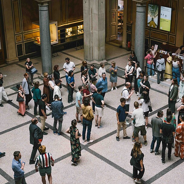 A group of people standing in a museum on a grey floor 
